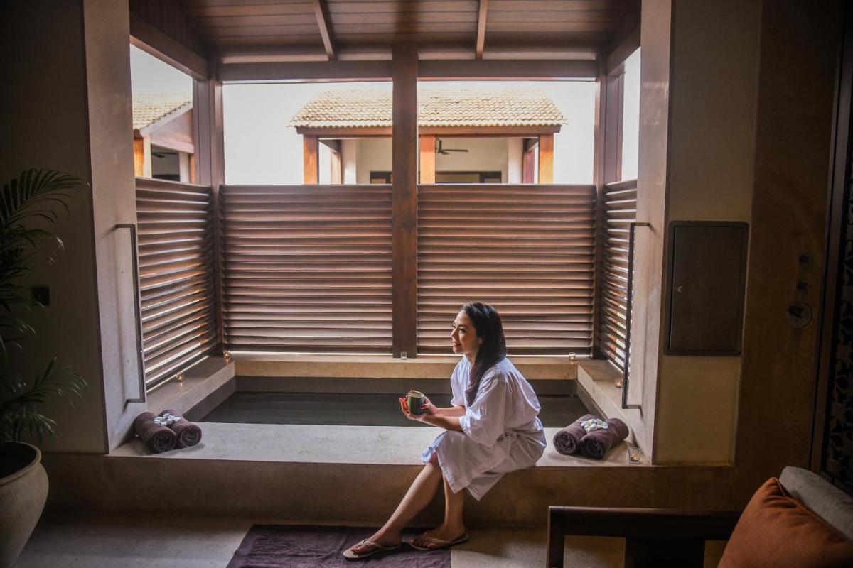 a woman sitting on a window sill in a room at Grand Hyatt Goa in Panaji a woman sitting on a window sill in a room at Grand Hyatt Goa in Panaji