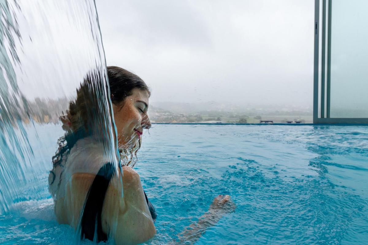 uma mulher em uma piscina com um respingo em In Gold Hotel & Spa em Águeda uma mulher em uma piscina com um respingo em In Gold Hotel & Spa em Águeda
