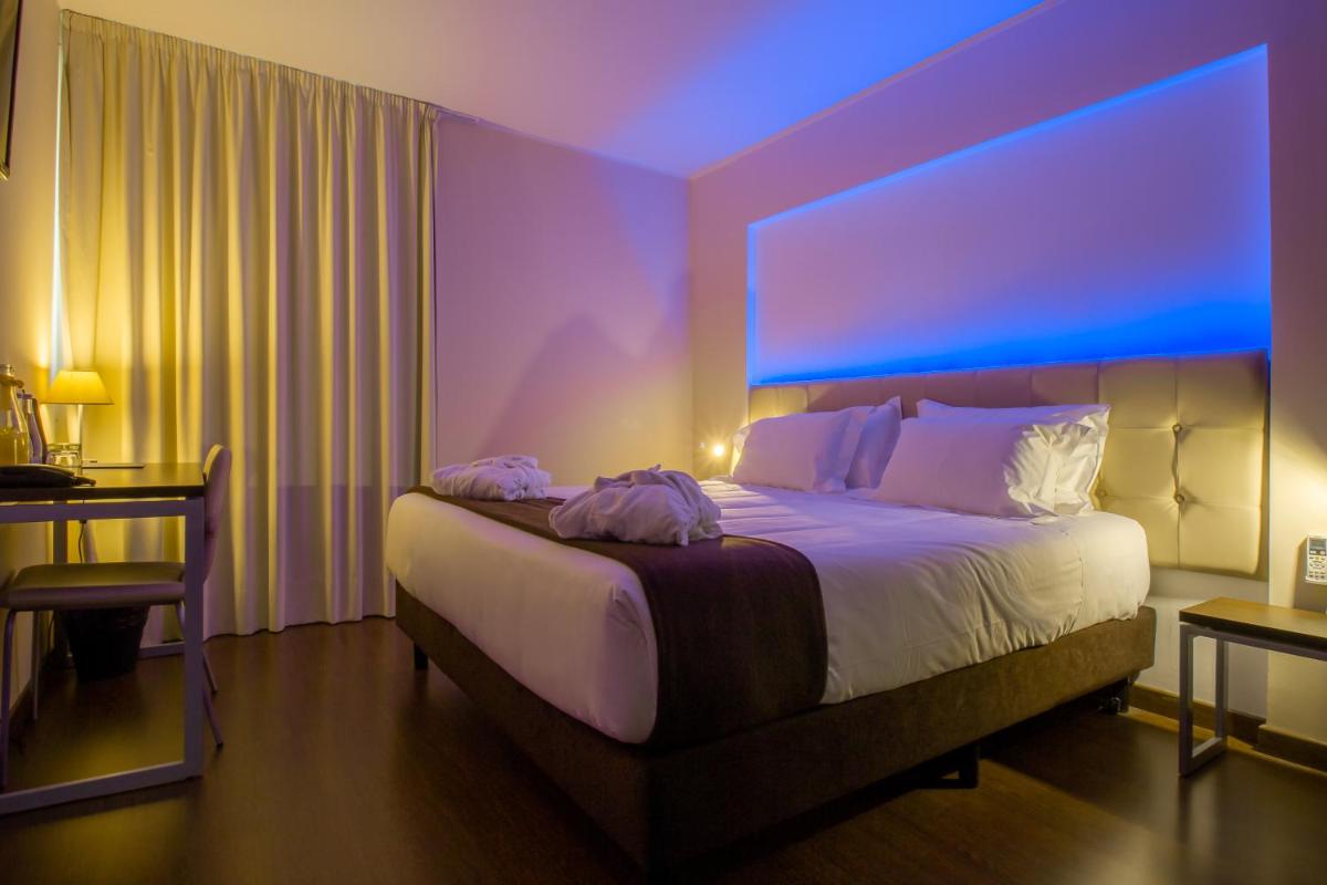 um quarto com uma cama grande com luz azul em In Gold Hotel & Spa em Águeda um quarto com uma cama grande com luz azul em In Gold Hotel & Spa em Águeda