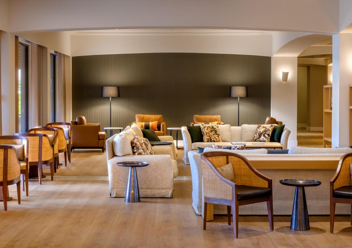 uma sala de espera com sofás, cadeiras e mesas em Evora Hotel em Évora