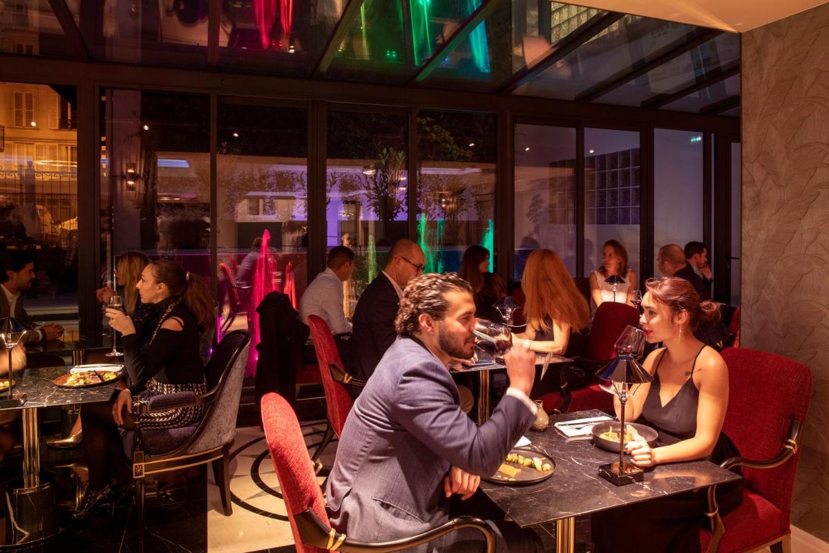 un groupe de personnes assises à des tables dans un restaurant dans l'établissement Paris j'Adore Hotel & Spa, à Paris 61 autres photos