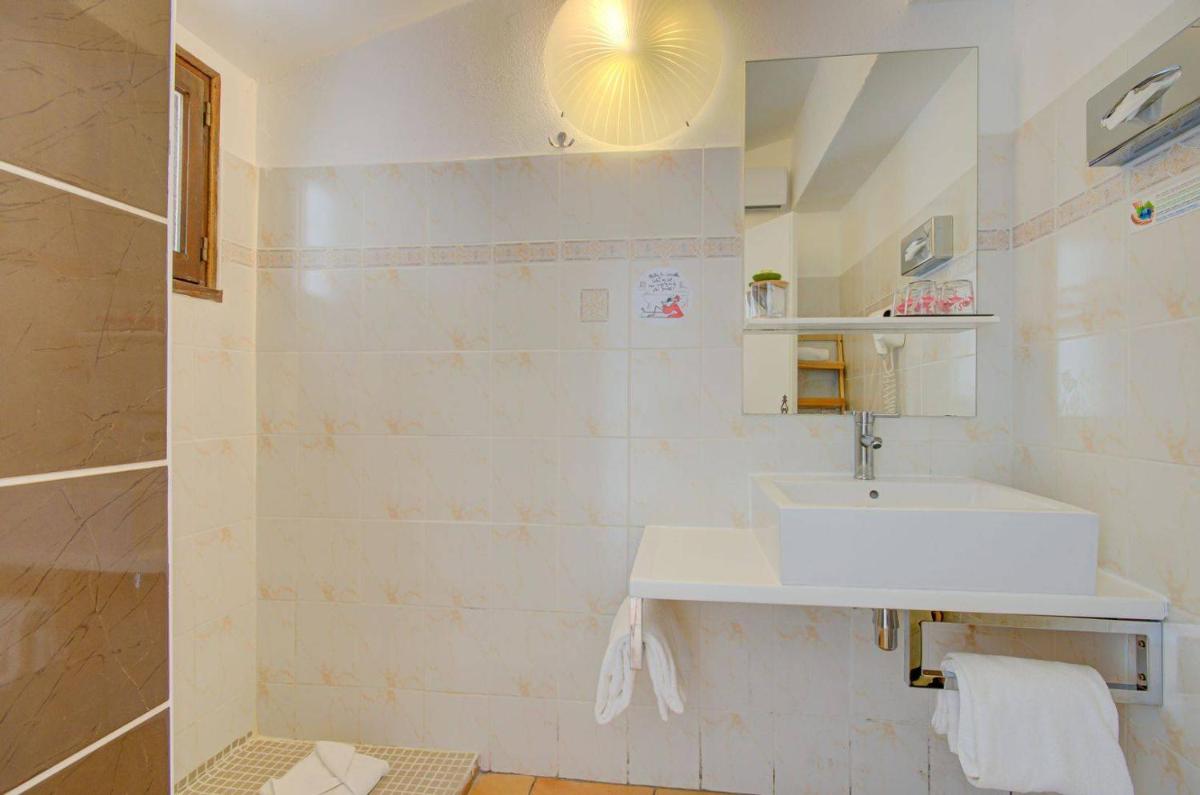 une salle de bain avec un lavabo et un miroir dans l'établissement Hôtel La Palunette, à Saintes-Maries-de-la-Mer 36 autres photos