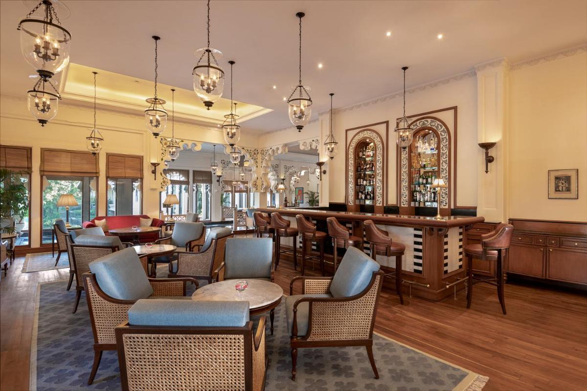 a restaurant with chairs and tables and a bar at Trident Udaipur in Udaipur