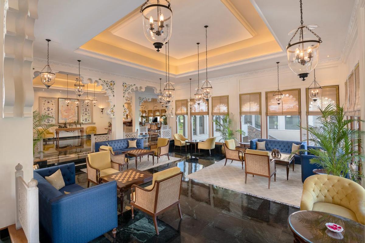 a lobby with chairs and tables and chandeliers at Trident Udaipur in Udaipur