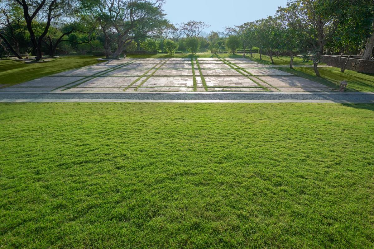 an empty road in a park with green grass at Trident Udaipur in Udaipur
