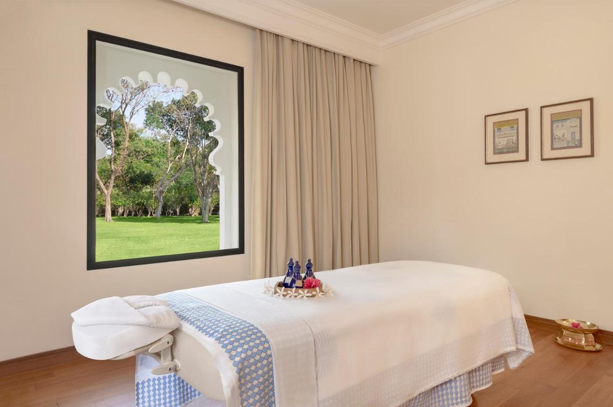 a white room with a bed with a table at Trident Udaipur in Udaipur