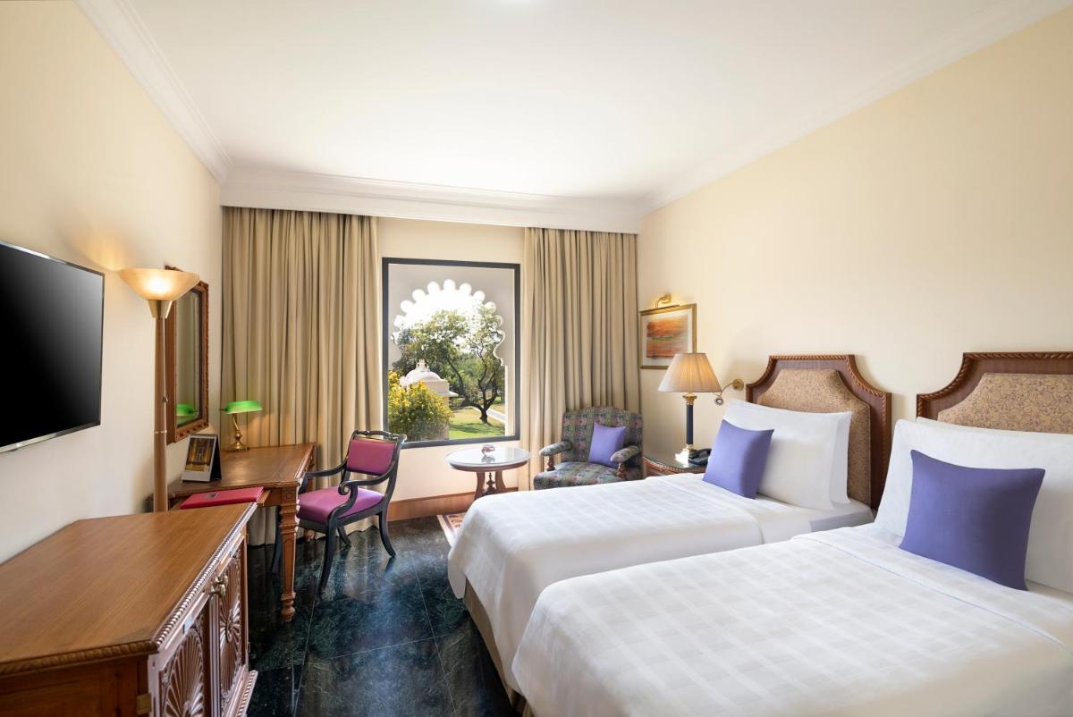 a hotel room with two beds and a desk at Trident Udaipur in Udaipur