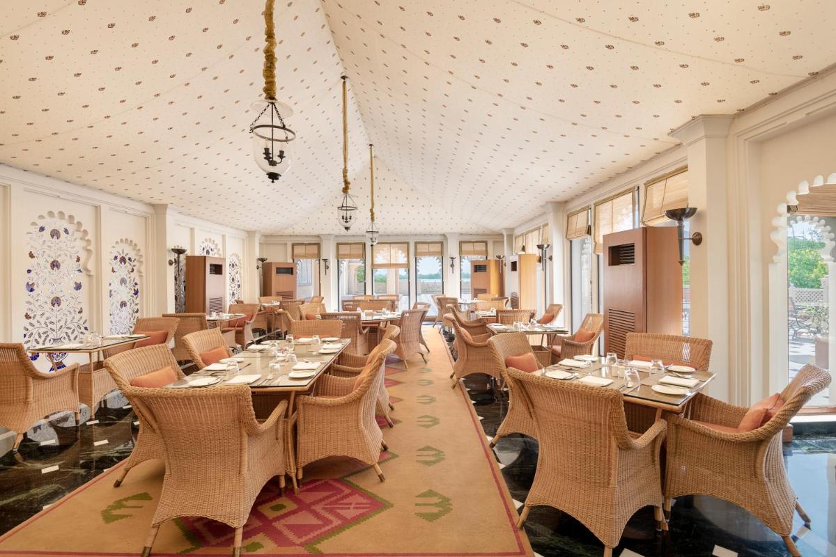 a dining room with tables and chairs and windows at Trident Udaipur in Udaipur