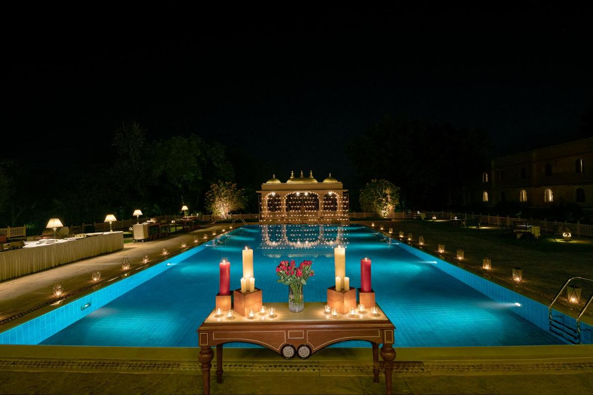 a swimming pool with candles and a table with flowers at Trident Udaipur in Udaipur