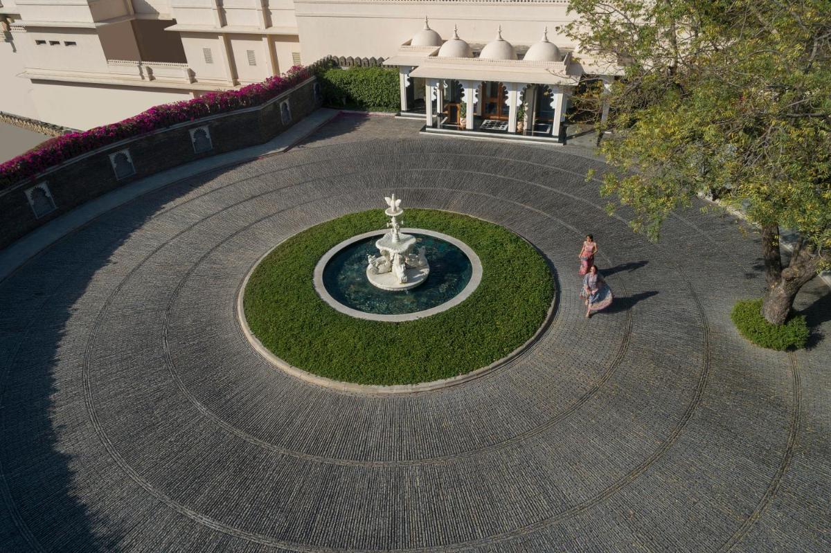 a woman walking around a fountain in a courtyard at Trident Udaipur in Udaipur