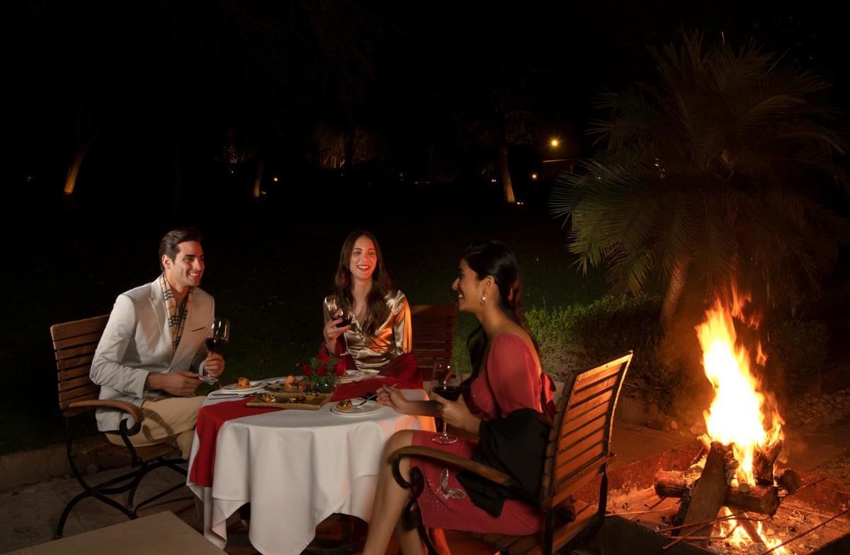 a group of people sitting around a table by a fire at Trident Udaipur in Udaipur