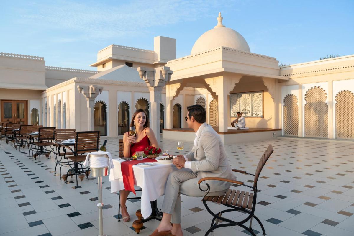 a man and woman sitting at a table in front of a building at Trident Udaipur in Udaipur