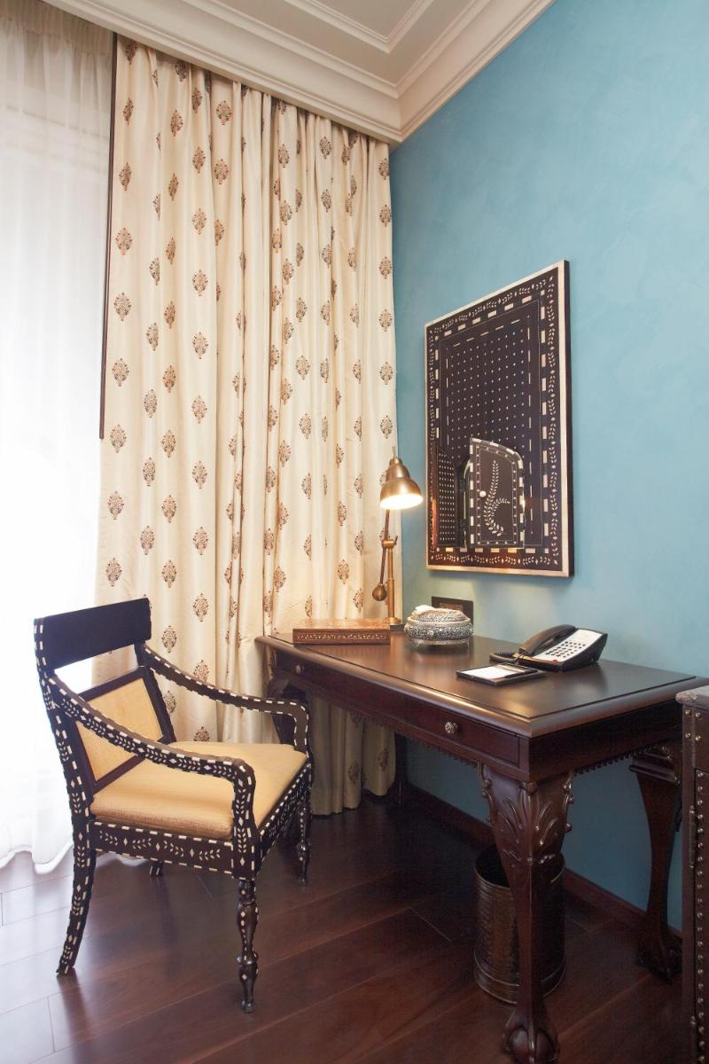 a desk in a room with a chair and a lamp at Fairmont Jaipur in Jaipur
