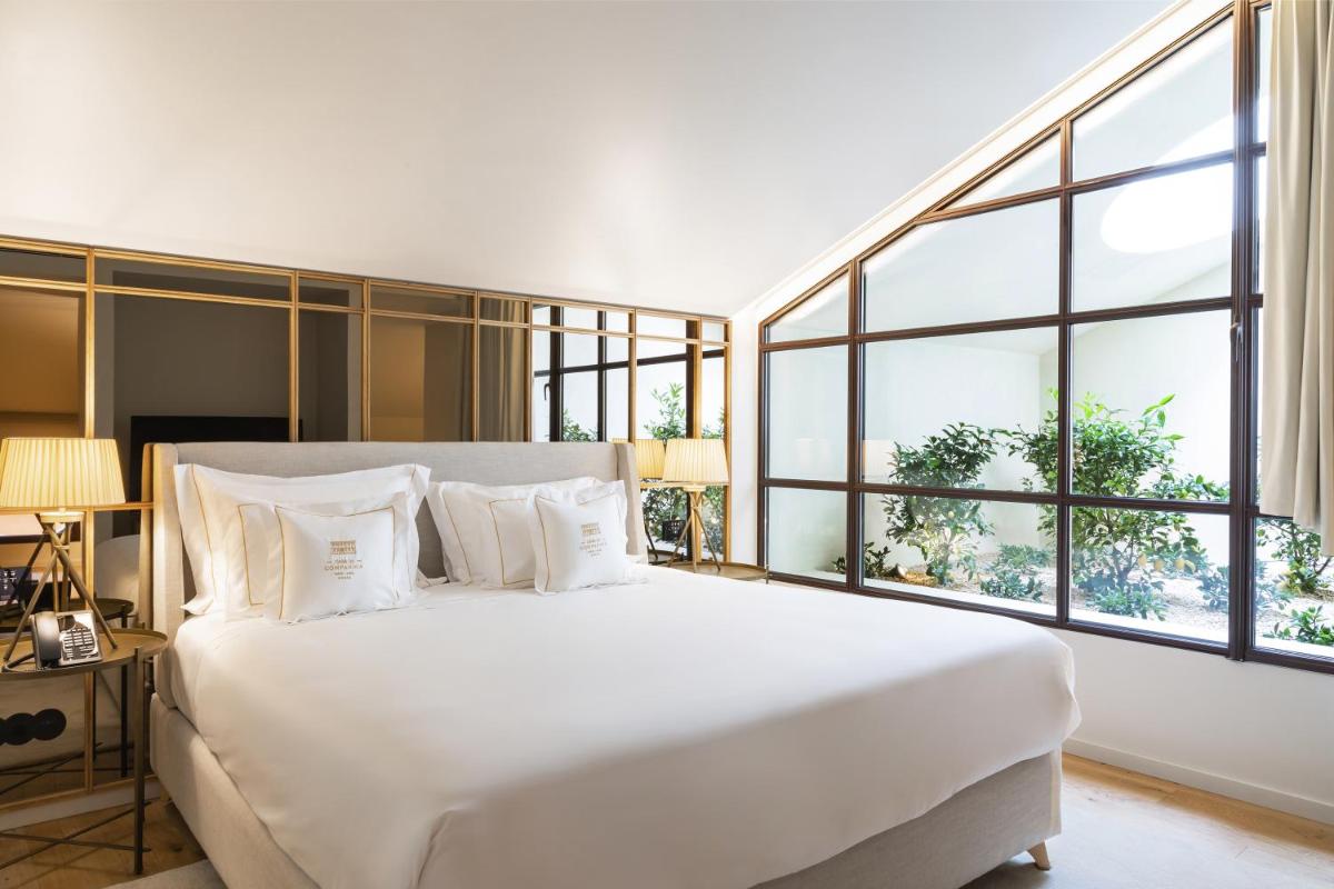 um quarto com uma grande cama branca com janelas em Casa da Companhia Hotel & Spa, Vignette Collection by IHG no Porto