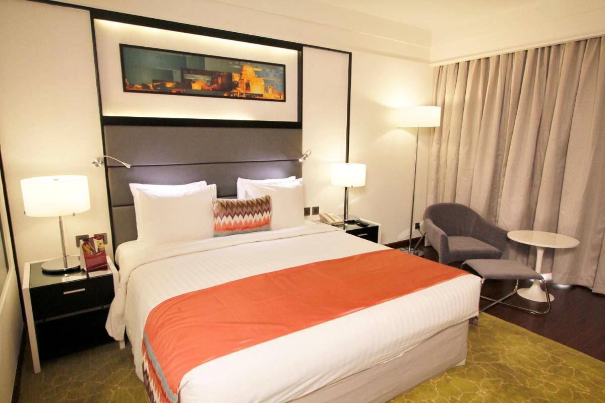 a hotel room with a large bed and a chair at Crowne Plaza Pune City Centre by IHG in Pune