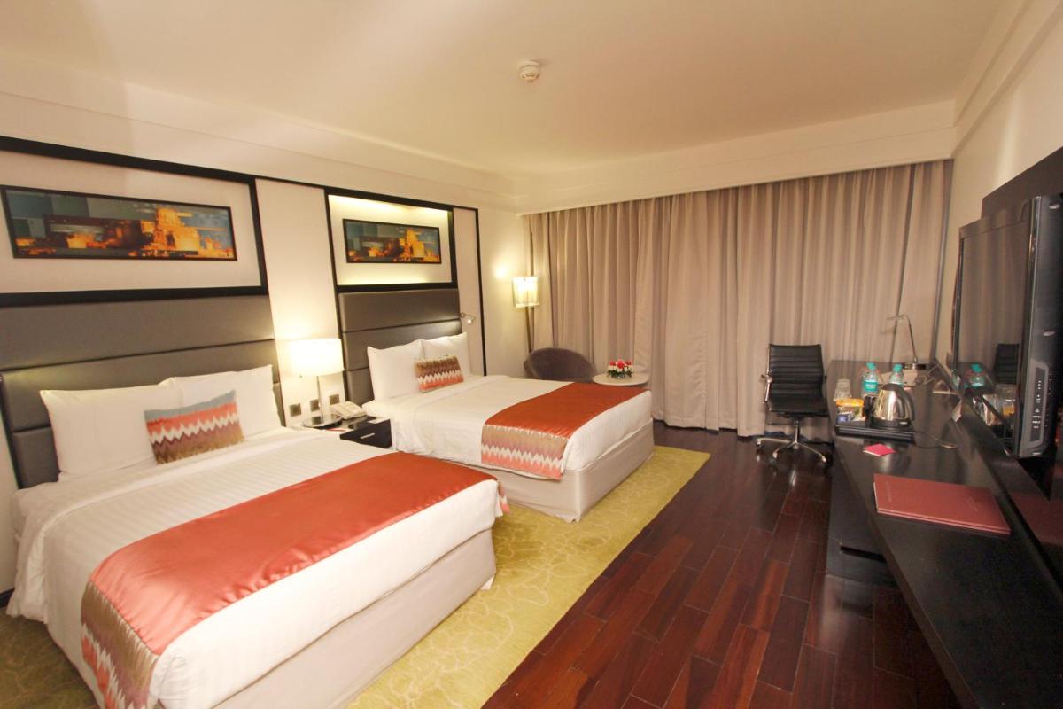 a hotel room with two beds and a desk at Crowne Plaza Pune City Centre by IHG in Pune