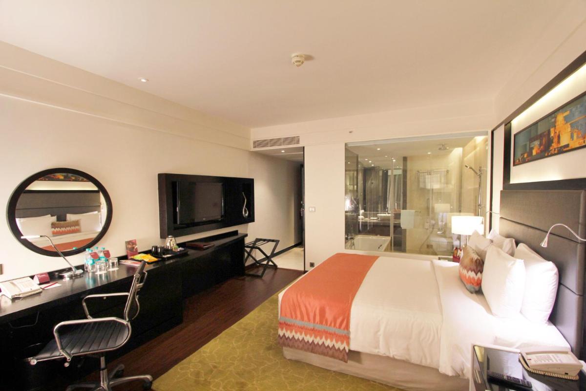 a bedroom with a bed and a desk and a television at Crowne Plaza Pune City Centre by IHG in Pune