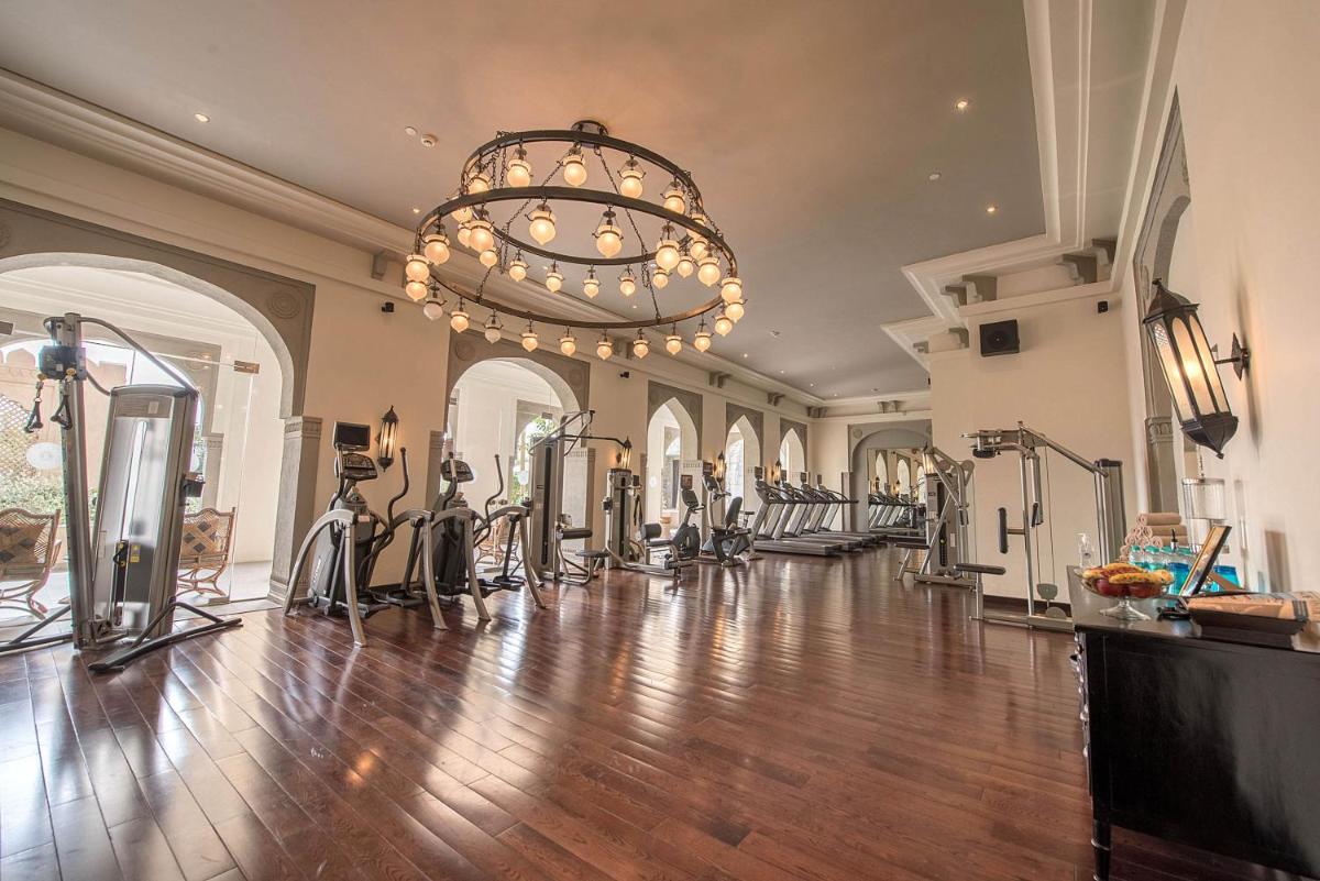 a gym with a chandelier and a large room with exercise bikes at Fairmont Jaipur in Jaipur