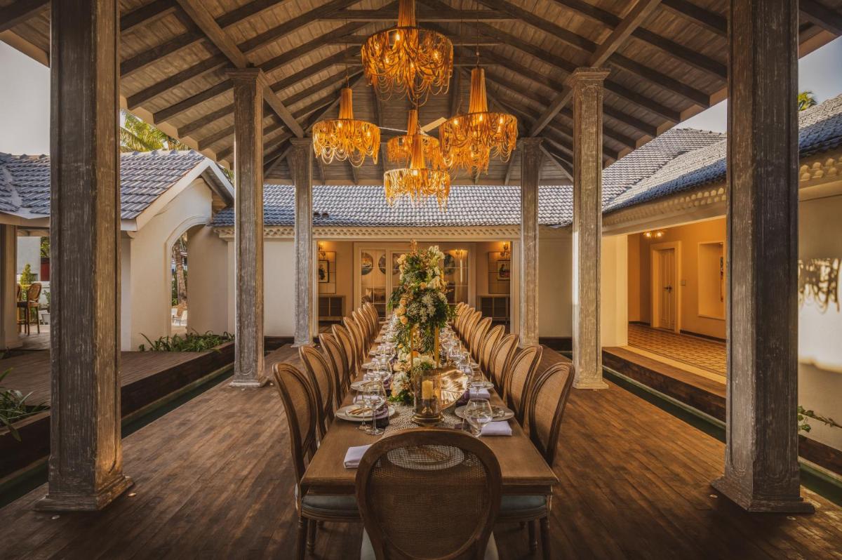 a dining room with a long table and chandeliers at MansionHaus in Anjuna