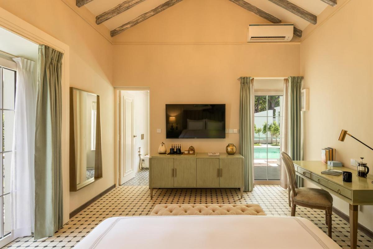 a large room with a tv and a desk and a tub at MansionHaus in Anjuna