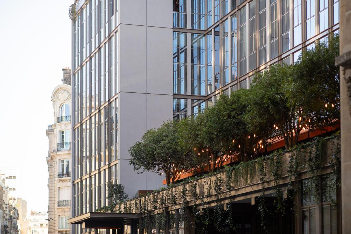 un grand bâtiment blanc avec une tour d'horloge dans l'établissement Brach Paris - Evok Collection, à Paris