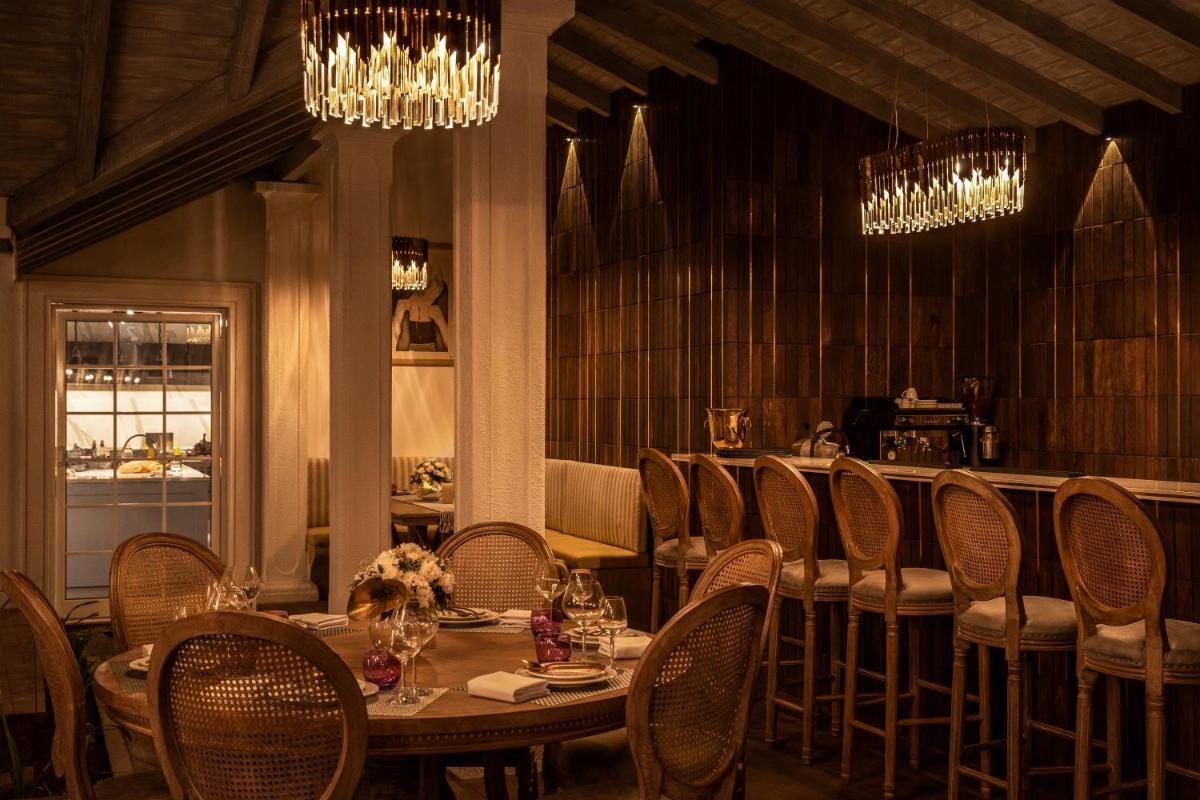 a dining room with a table and chairs and chandeliers at MansionHaus in Anjuna