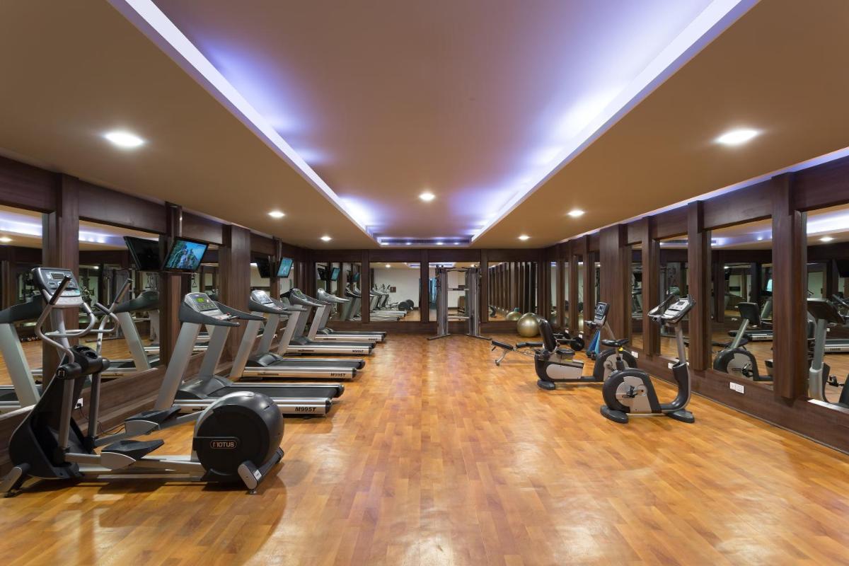a gym with a row of treadmills and ellipticals at Welcomhotel by ITC Hotels, Dwarka, New Delhi in New Delhi a gym with a row of treadmills and ellipticals at Welcomhotel by ITC Hotels, Dwarka, New Delhi in New Delhi