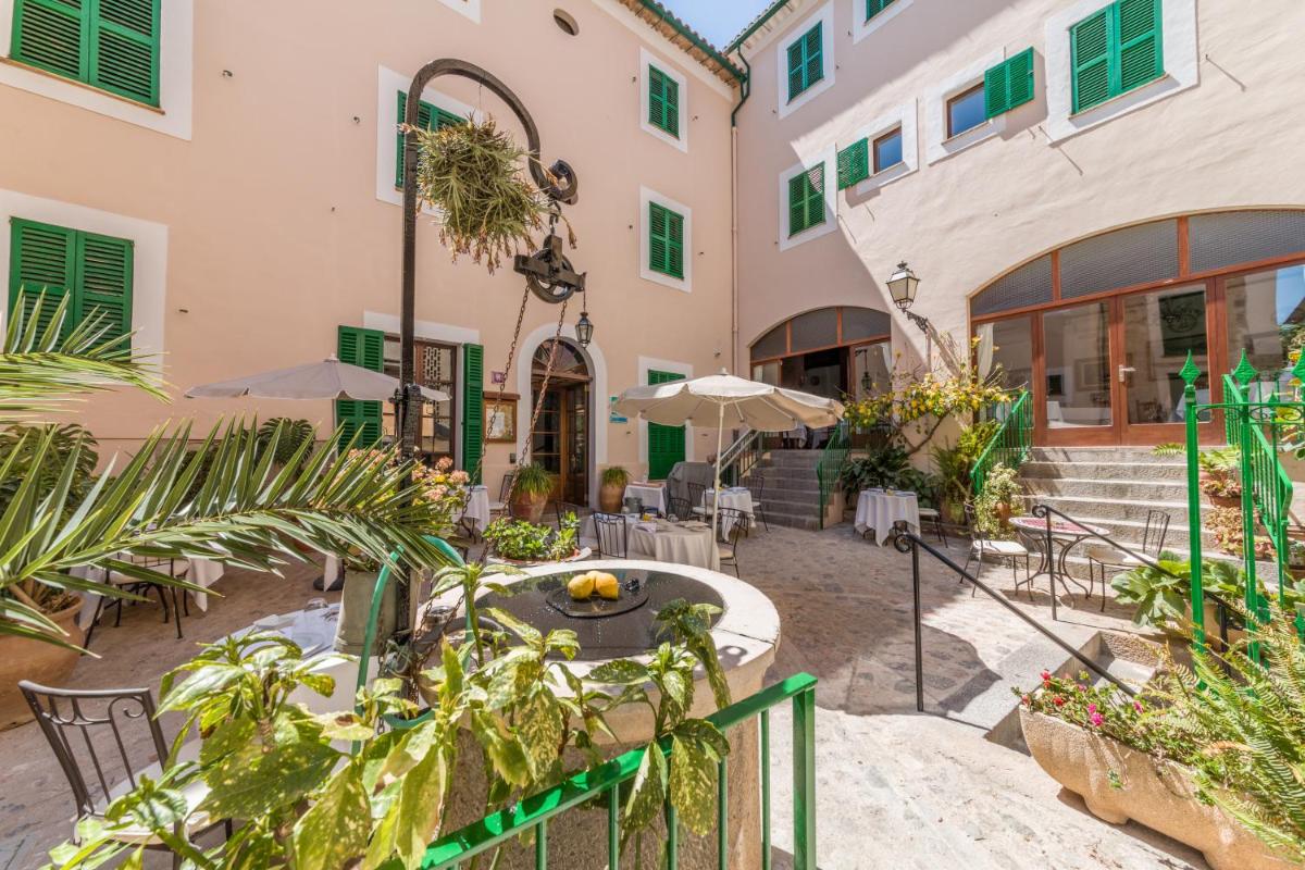 Un patio con mesas y sillas en un edificio. en Hotel El Guía, en Sóller