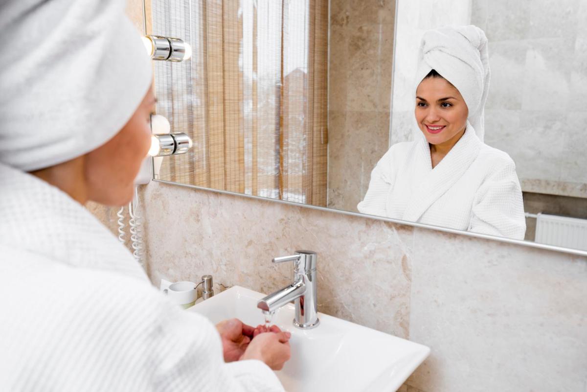 a woman standing in front of a bathroom mirror at Holiday Inn Mumbai International Airport by IHG in Mumbai