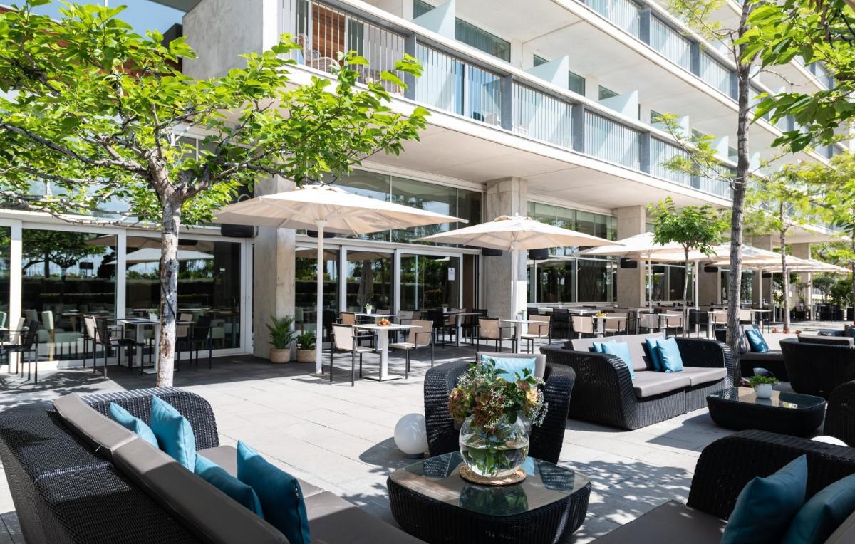 un patio al aire libre con sofás, mesas y sombrillas en Atenea Port Barcelona Mataró, en Mataró
