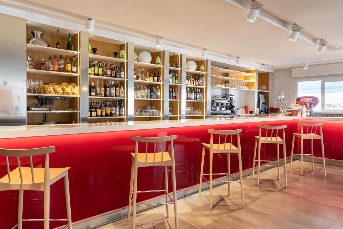 un bar rojo con taburetes en un restaurante en Hotel Montecarlo Spa & Wellness, en Roses