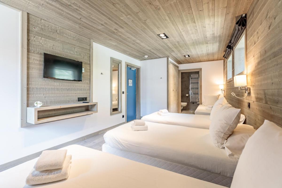 une chambre d'hôtel avec trois lits et une télévision dans l'établissement Victoria Lodge, Friendly Hotel, à Val dʼIsère