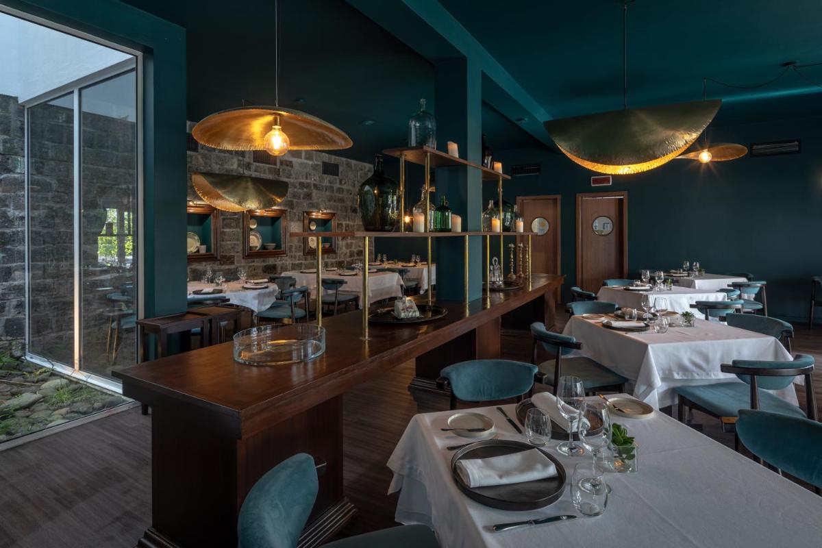 um restaurante com mesas e cadeiras e uma grande janela em Senhora da Rosa, Tradition & Nature Hotel em Ponta Delgada