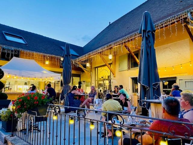 un groupe de personnes assises dans un restaurant avec des parasols dans l'établissement Domaine de Suzel, à Vignieu