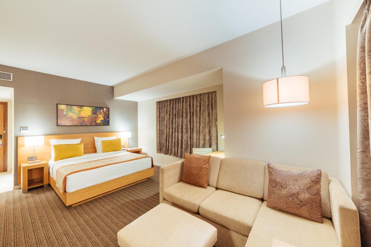 a hotel room with a bed and a couch at Novotel Lucknow Gomti Nagar in Lucknow