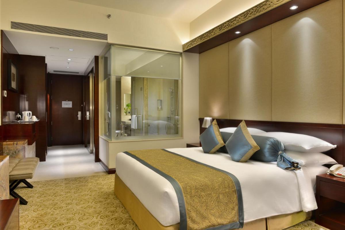a bedroom with a large bed and a bathroom at Crowne Plaza Ahmedabad City Centre by IHG in Ahmedabad