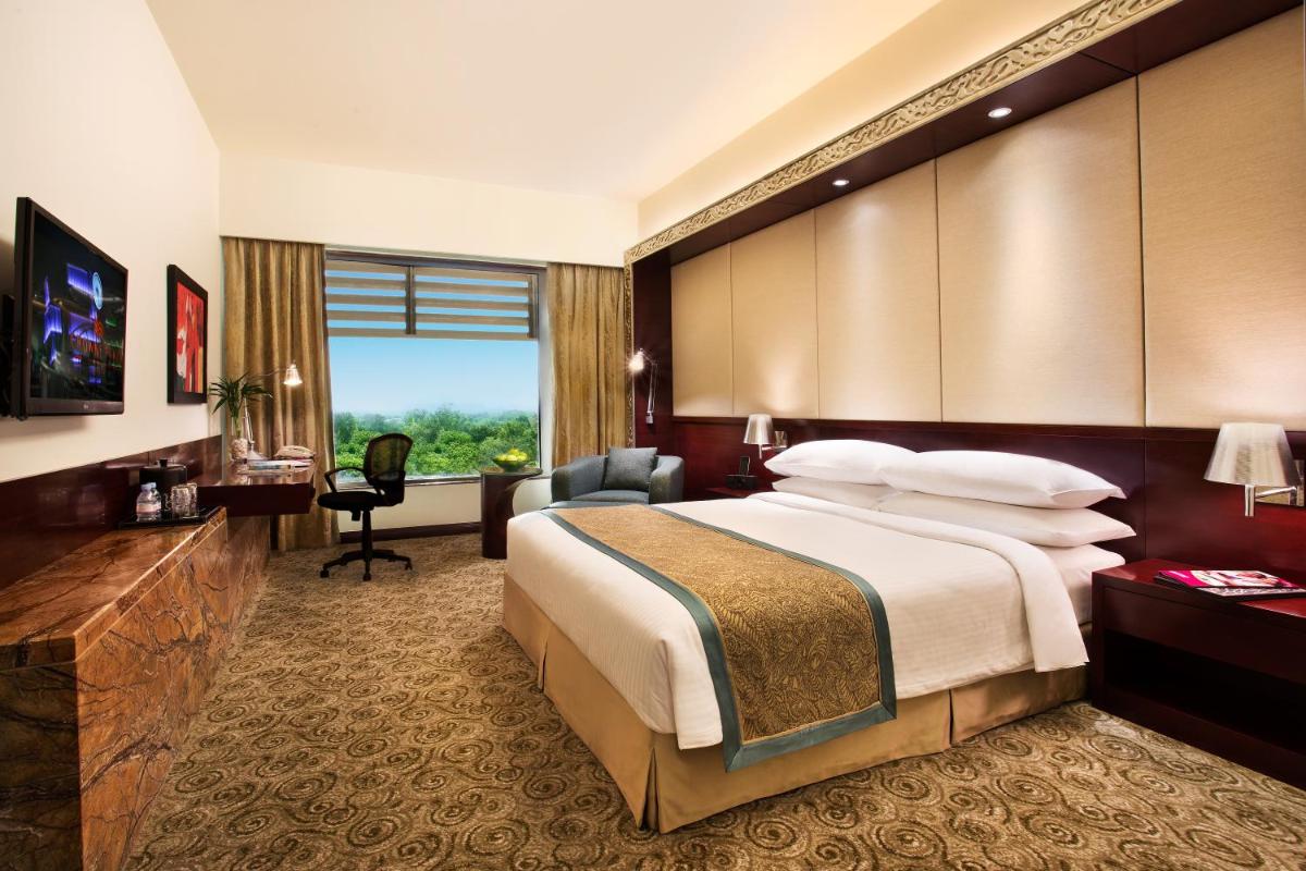 a hotel room with a large bed and a desk at Crowne Plaza Ahmedabad City Centre by IHG in Ahmedabad