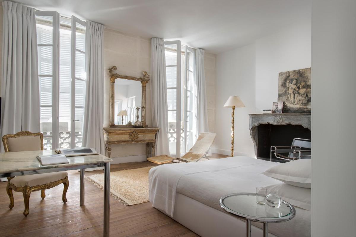 une chambre avec un lit, une table et un miroir dans l'établissement L'Hôtel Particulier, à Arles