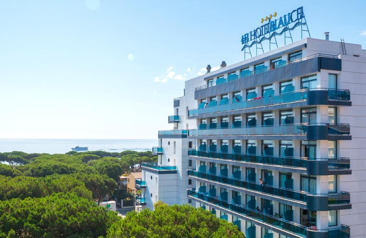 un gran edificio blanco con balcones azules y el océano en Hotel Blaucel, en Blanes