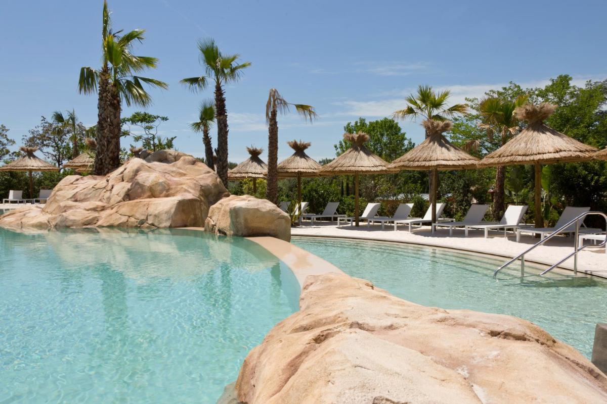 une grande piscine avec chaises et palmiers dans l'établissement Domaine du Mas De Pierre, à Saint-Paul-de-Vence