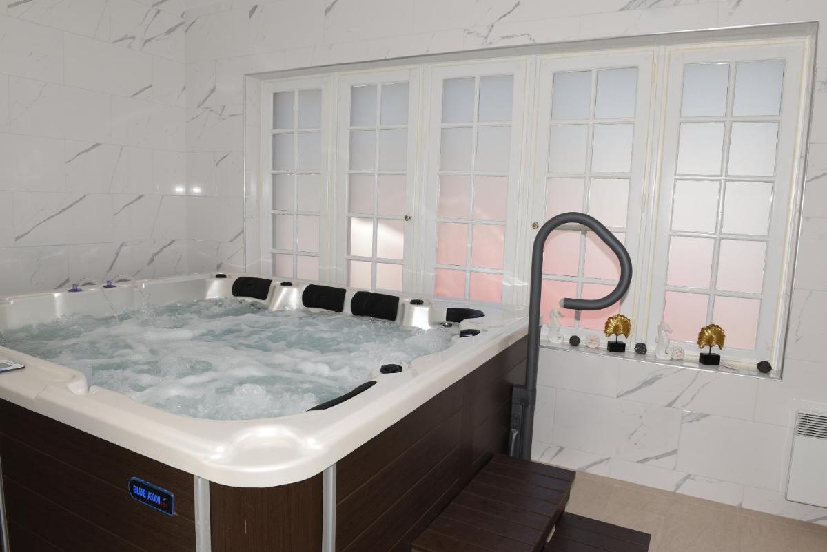 une grande baignoire dans une salle de bain aux murs blancs dans l'établissement Hôtel Normandie Spa, à Bagnoles-de-l'Orne
