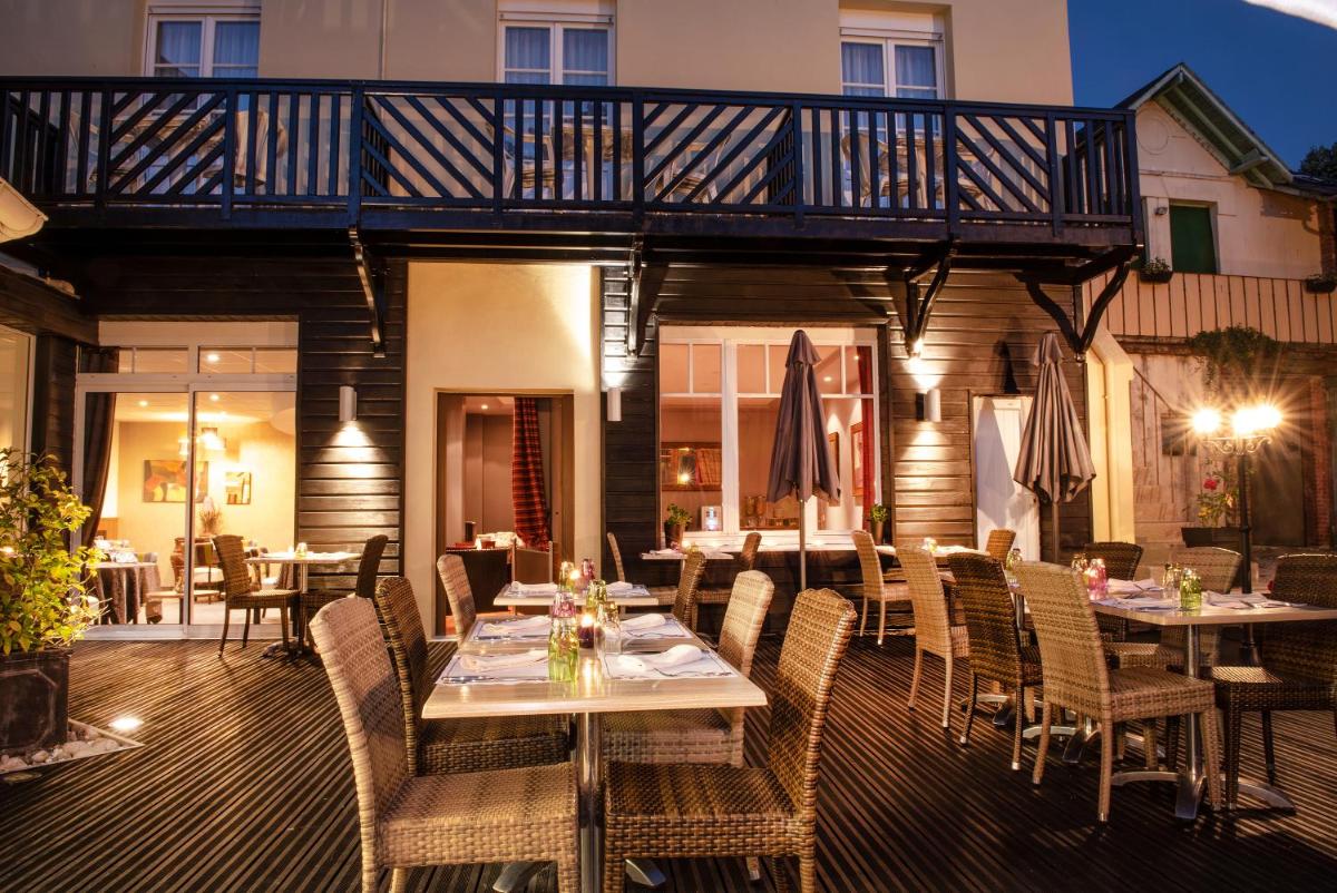un restaurant avec des tables et des chaises sur une terrasse dans l'établissement Hôtel Normandie Spa, à Bagnoles-de-l'Orne