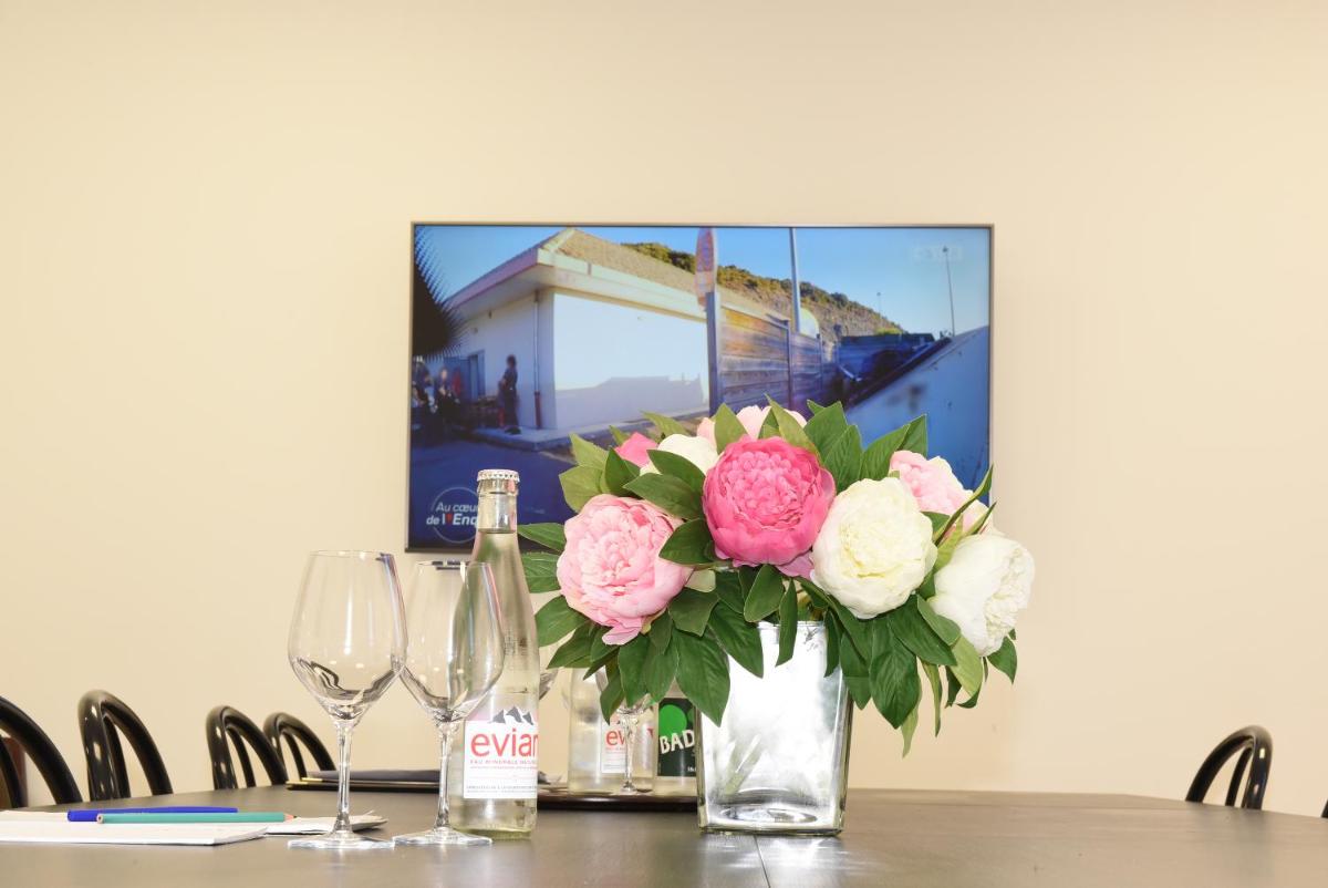 un vase de fleurs sur une table avec des verres à vin dans l'établissement Hôtel Normandie Spa, à Bagnoles-de-l'Orne