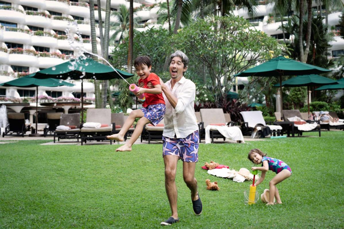 a man and two children playing with a water hose at Shangri-La Singapore in Singapore