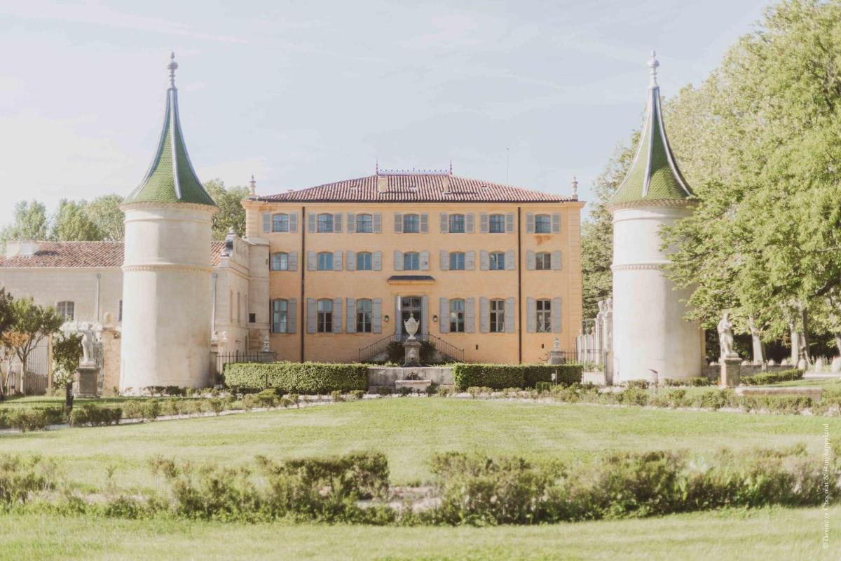 un grand bâtiment avec deux tours dans un champ dans l'établissement Château de Fonscolombe, à Le Puy-Sainte-Réparade