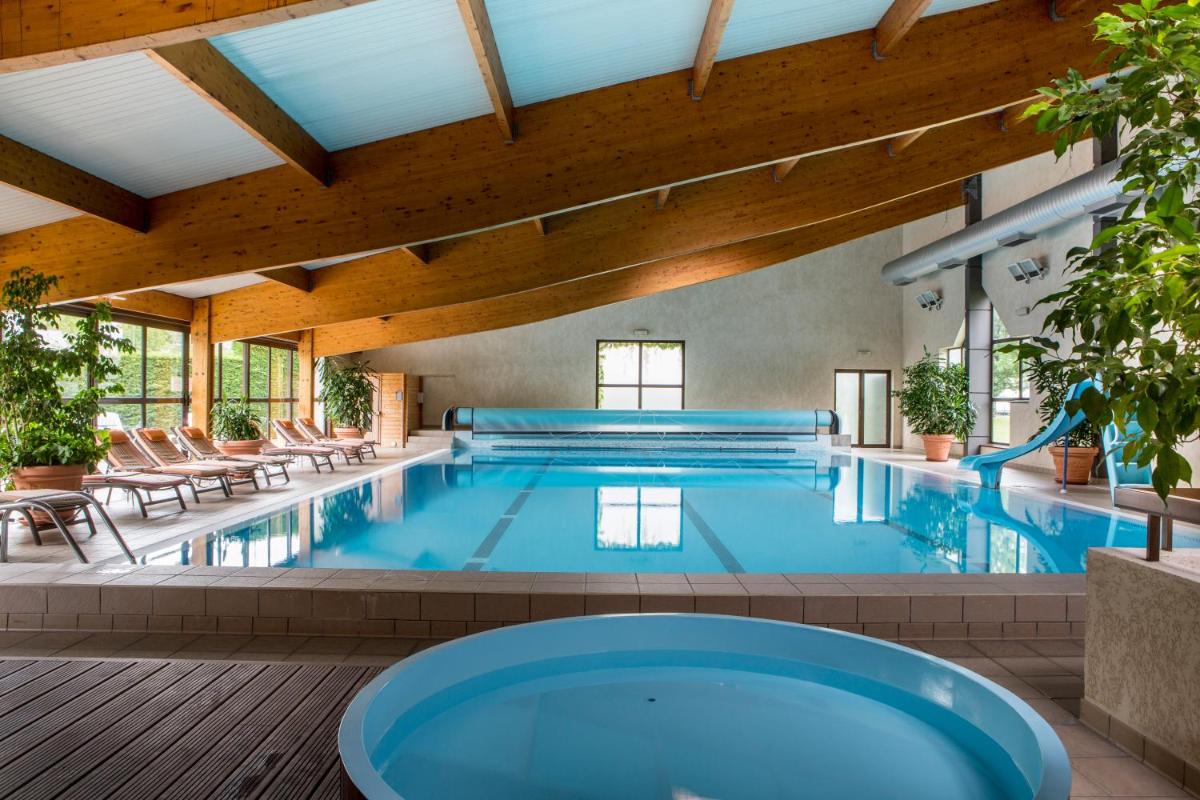 une grande piscine avec des chaises et un bassin de natation dans l'établissement Best Western Le Relais de Laguiole Hôtel & Spa, à Laguiole