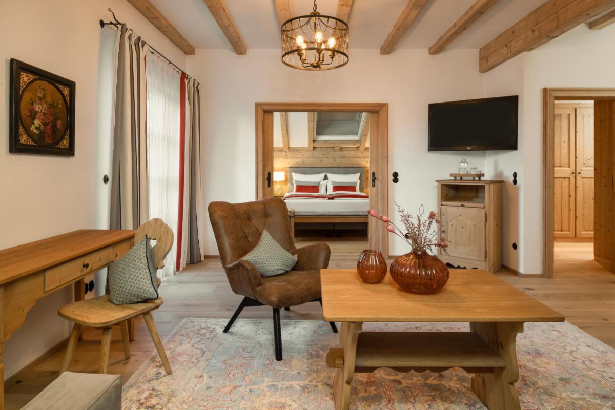 ein Wohnzimmer mit Tisch und ein Schlafzimmer in der Unterkunft Hotel Gut Ising in Chieming
