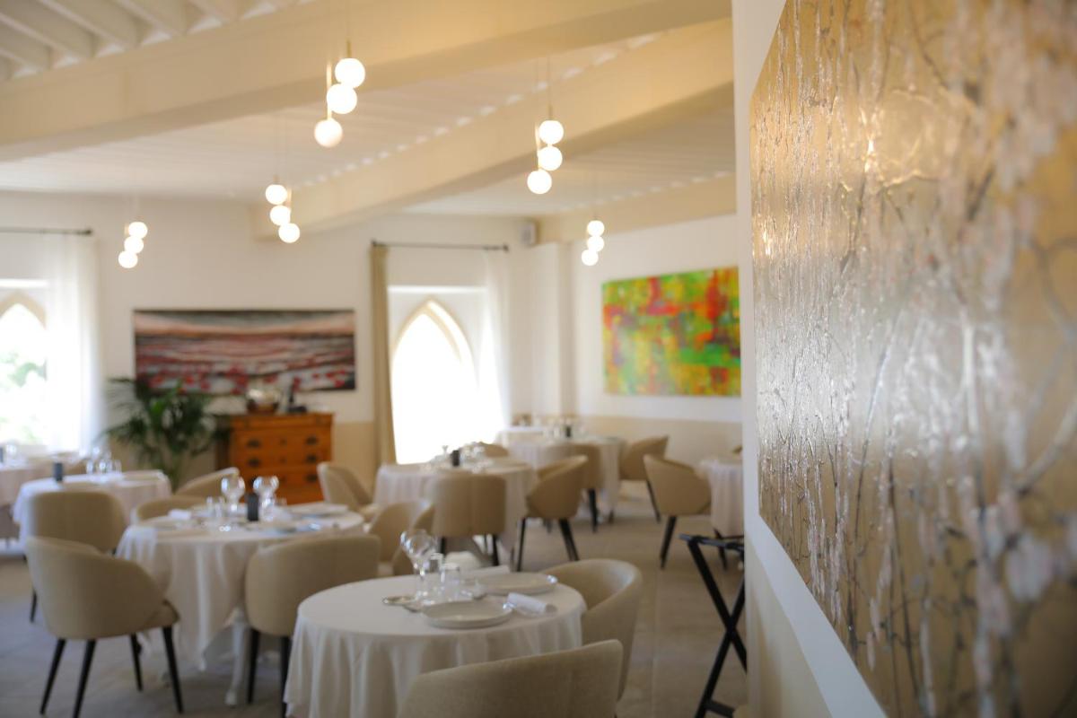 une salle à manger avec des tables et des chaises blanches dans l'établissement Hostellerie du Château des Fines Roches, à Châteauneuf-du-Pape