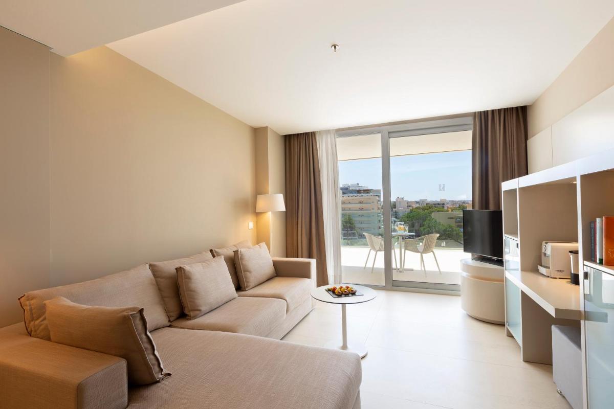 Una sala de estar con un sofá y un televisor. en Hipotels Gran Playa de Palma, en Playa de Palma