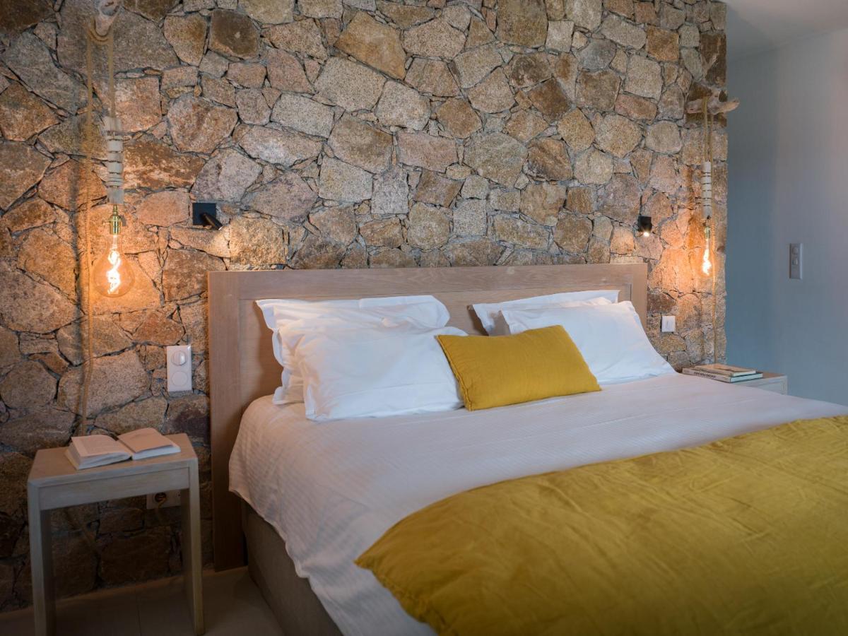 une chambre avec un lit avec un mur en pierre dans l'établissement Hotel A Piattatella, à Monticello